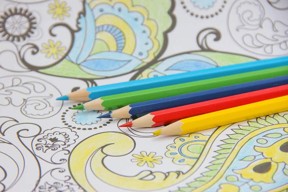crayons on a coloring book backgorund for kids art therapy