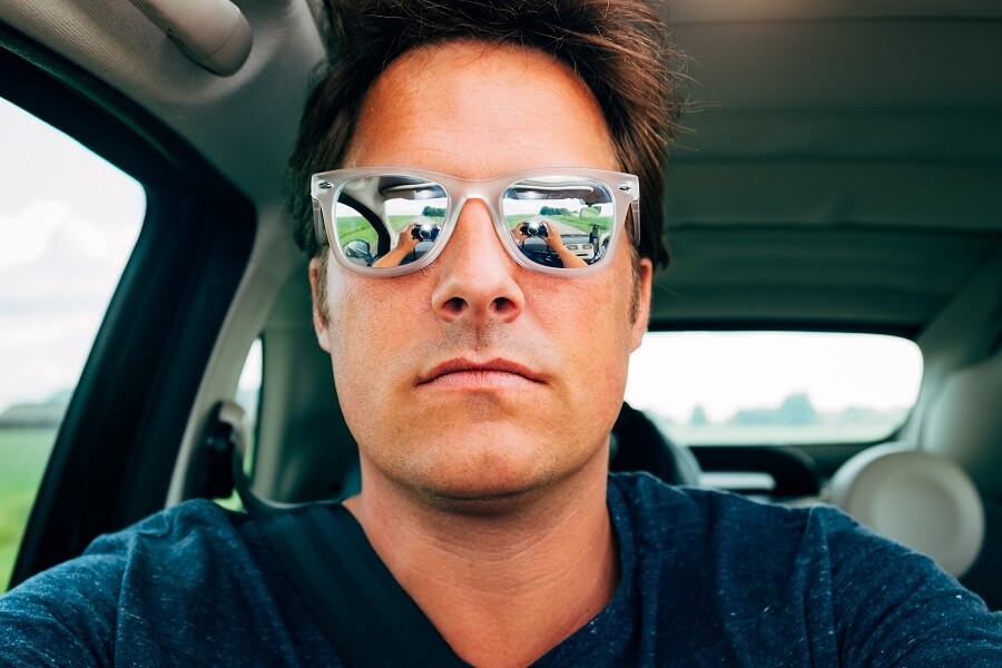 man taking selfie in car with sunglasses on