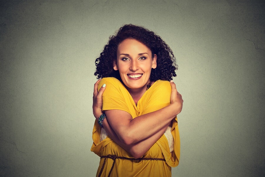 woman smiling with her arms around herself