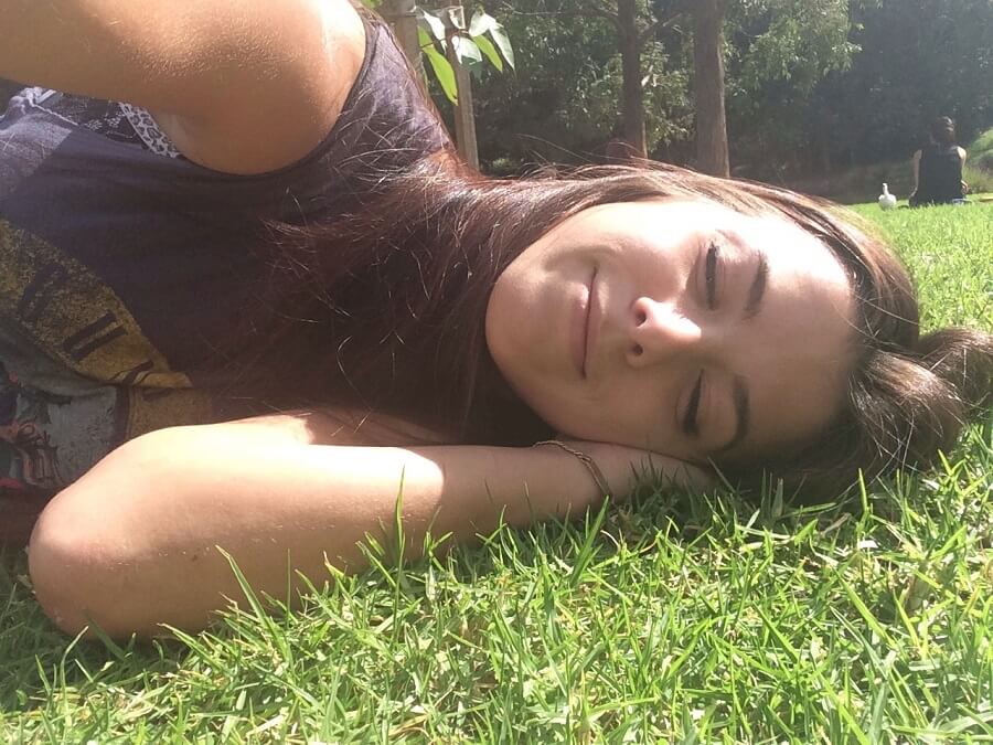 girl taking selfie while laying on the grass with eyes closed