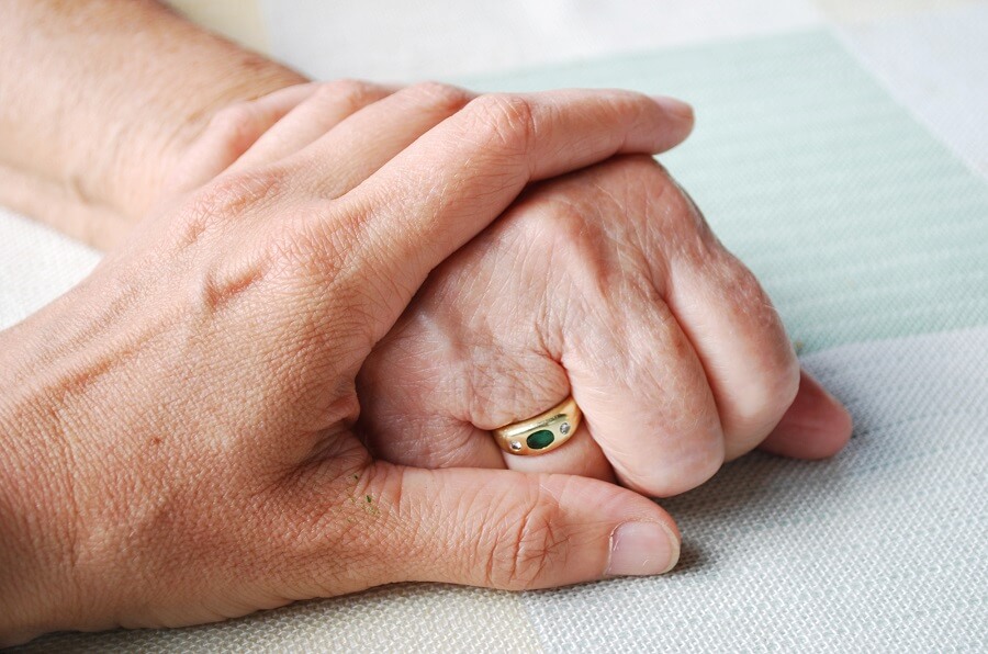 young person's hand resting on an old person's hand