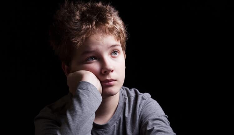 teen boy looking sad black background