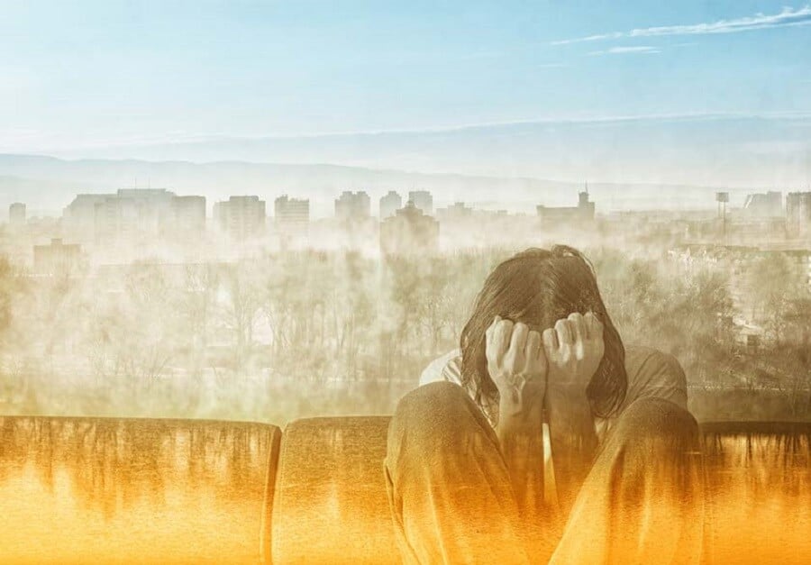 man covering his face while on sofa with city in the background