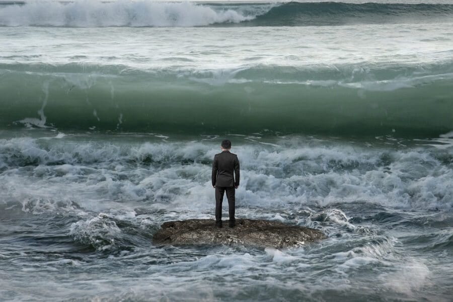 businessman standing on a rock in the sea