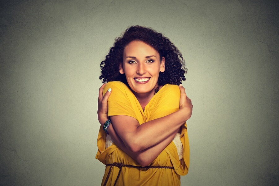 woman smiling with her arms around herself