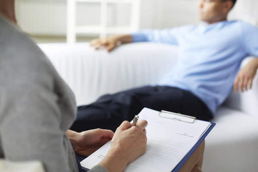 therapist writing in chart while the patient is in the background