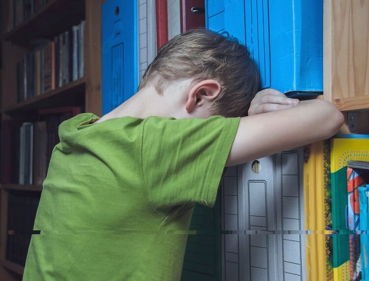 child with green shirt leaning on a shelf