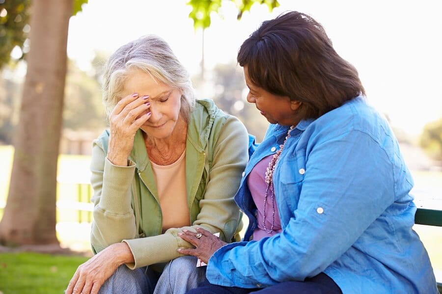 a woman comforting another in the park