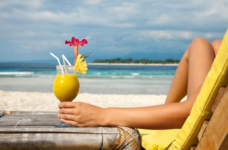 woman at the beach holding a cocktail