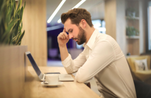 online therapy: man with hand on temple looking at laptop